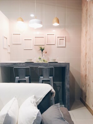 A modern room with a bed, two chairs, a small table, and pendant lights.