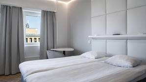 A modern hotel room with a large bed, a small table, and a view of the city through the window. - Omena Hotel Vaasa Espen (Vaasa)