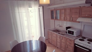Una cocina compacta con una mesa y sillas, armarios de madera, un microondas y un horno.