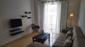 Una sala de estar con un sofá, televisor, una mesa de centro y una silla.