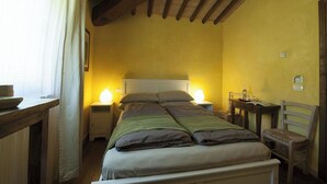A bedroom with a bed, bedside tables, a chair, and a nightstand. - Mulino Cintoia Chianti Toscana Pool, Sauna and Jacuzzi Experience (Greve in Chianti)