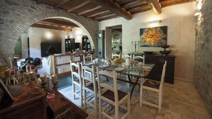 A rustic dining area with a stone archway, wooden beams, and a glass table set for dining. - Mulino Cintoia Chianti Toscana Pool, Sauna and Jacuzzi Experience (Greve in Chianti)