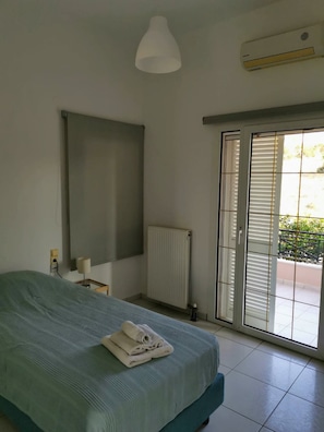 A bedroom with a bed, a radiator, a window with blinds, and a ceiling light. - Luxury Villa Zen Amazing View Near The Sea (Hersonissos)