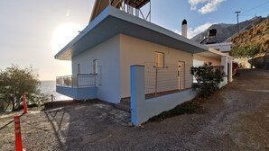 A coastal building with a balcony, a fenced area, and a view of the sea. - Amazing House Erato On The Sea South Creta (Archanes-Asterousia)
