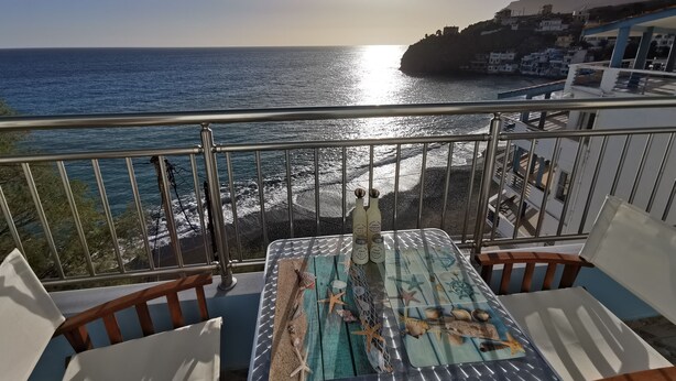 A balcony with a view of the sea, a table with sea-themed decorations, and bottles of oil and salt. - Amazing House Erato On The Sea South Creta (Archanes-Asterousia)