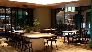 A modern restaurant with a central island, multiple seating arrangements, and large windows offering views of the cityscape. - Prince Smart Inn Ebisu (Tokyo)