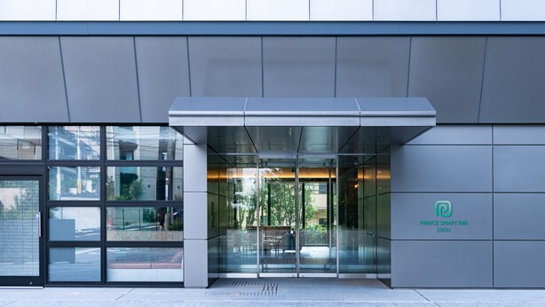 The exterior of a modern building with a glass entrance, a sign for Prince Smart Inn Ebisu, and a paved walkway. - Prince Smart Inn Ebisu (Tokyo)
