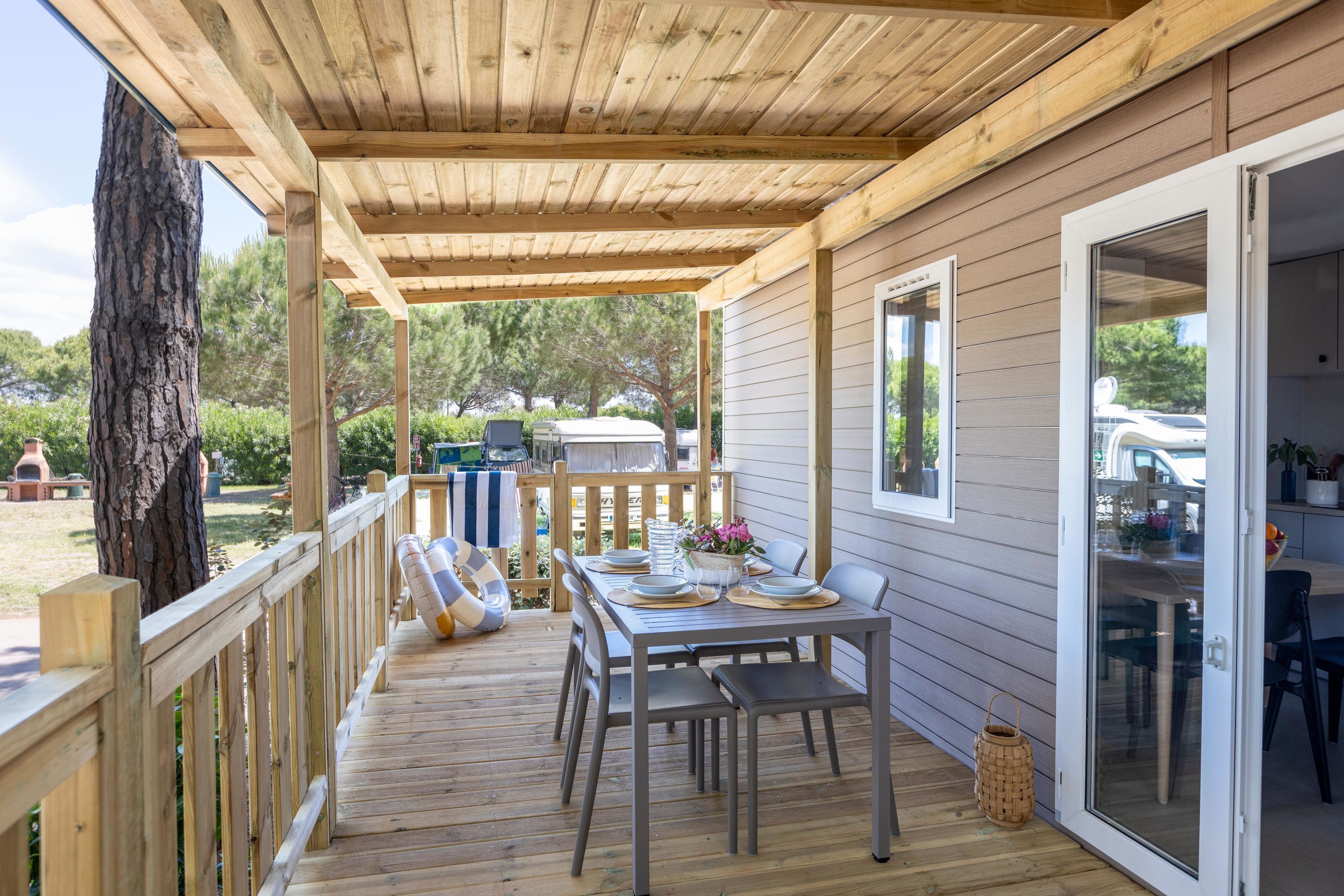 Une terrasse couverte avec une table dressée pour les repas, une balustrade en bois et une vue sur le jardin arrière.