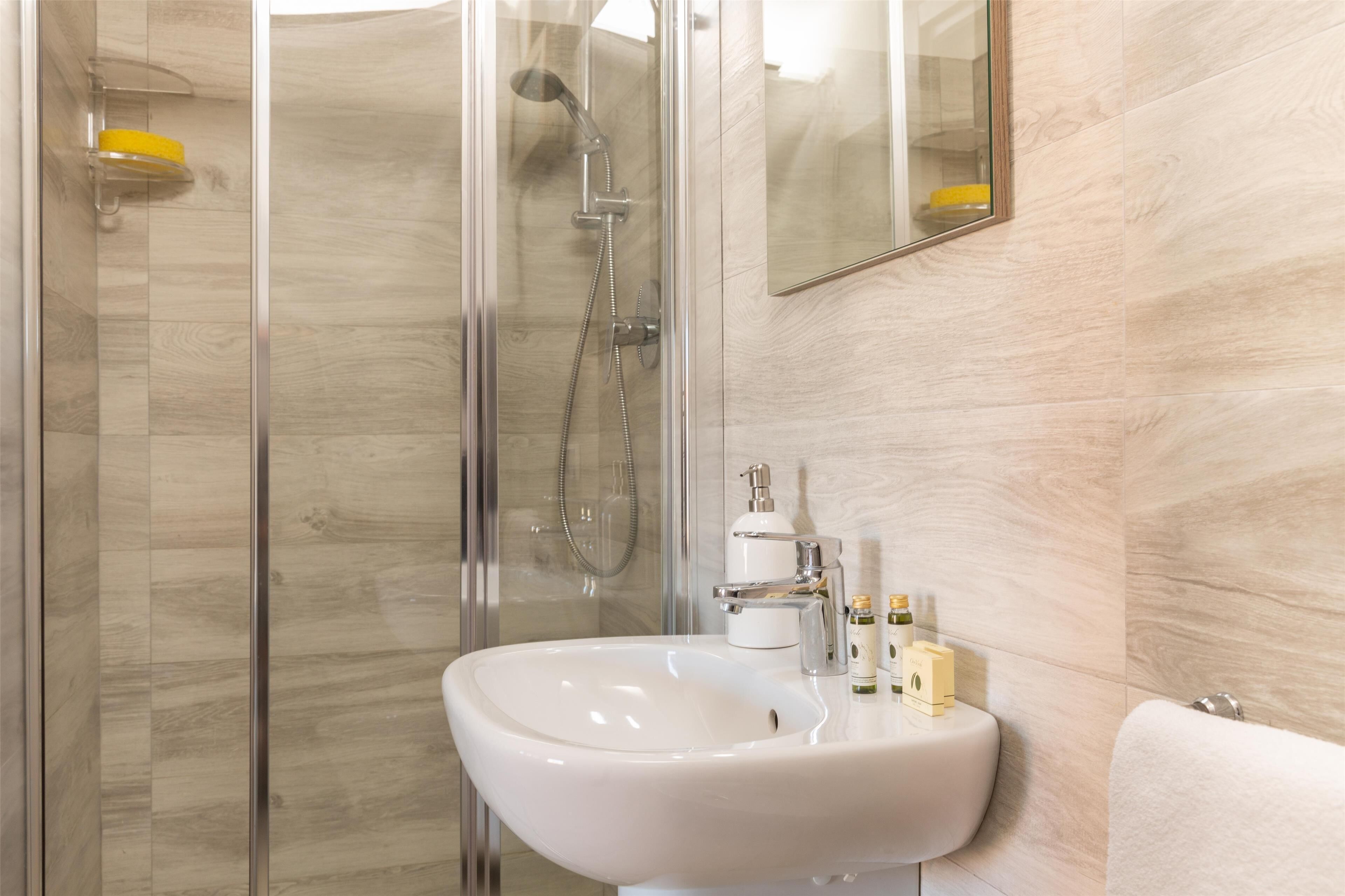 Een moderne badkamer met een douchecabine van glas, een wit wastafelmeubel en een spiegel.