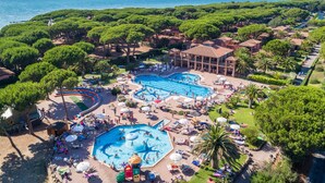 Un resort con varias piscinas, exuberante vegetación y vista al mar.