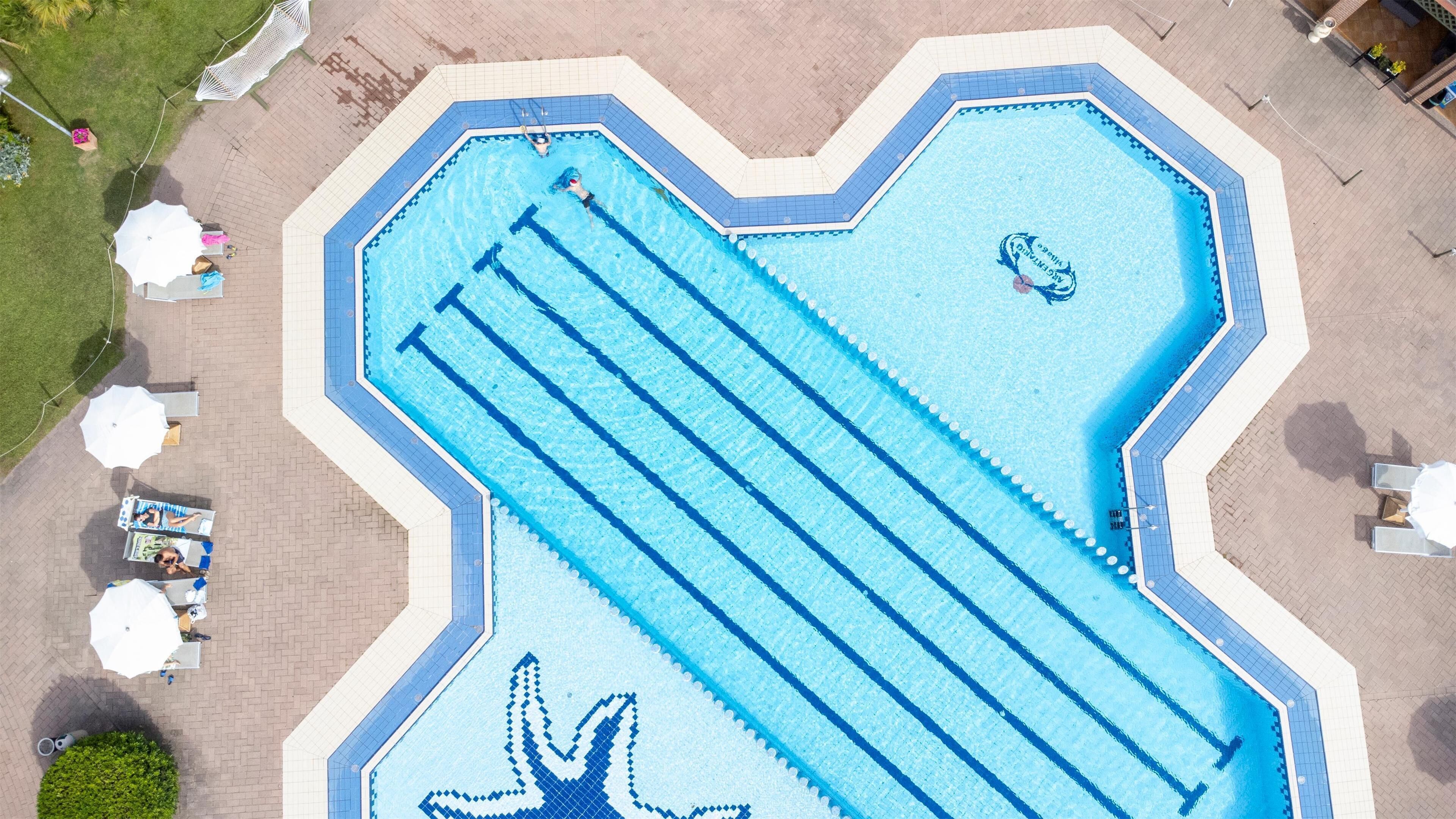An aerial view of a swimming pool with a unique starfish design, surrounded by lounge chairs and umbrellas.