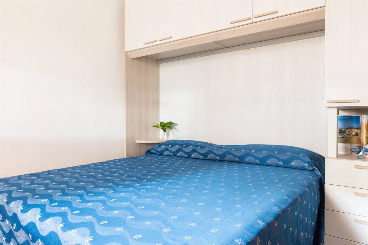 Une chambre à coucher avec un lit, une petite plante et une armoire intégrée.