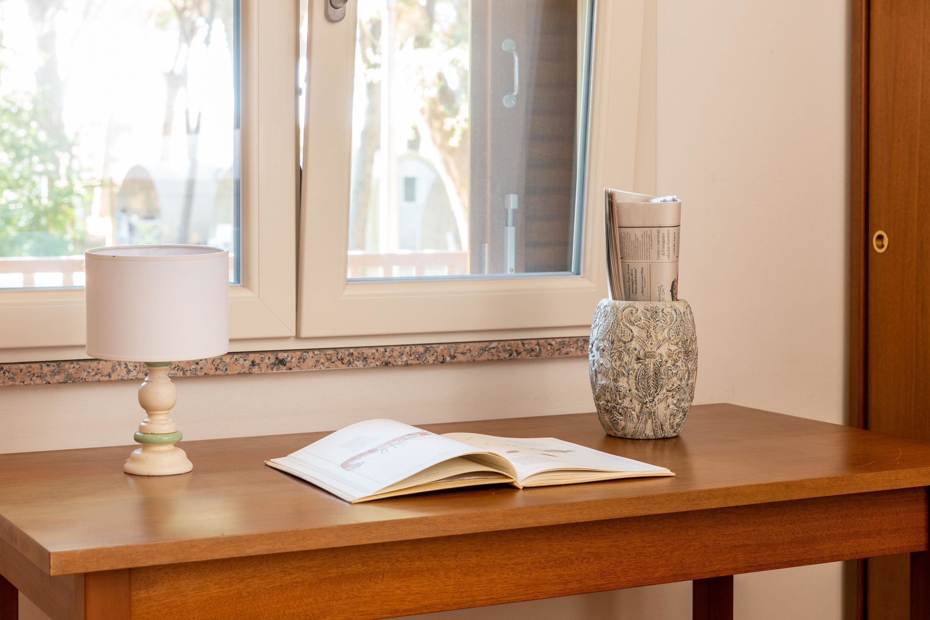 Een houten tafel met een lamp, een vaas en een open boek.