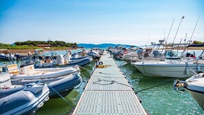 Un puerto deportivo con numerosos barcos amarrados a lo largo de un muelle, rodeado de agua y vegetación.