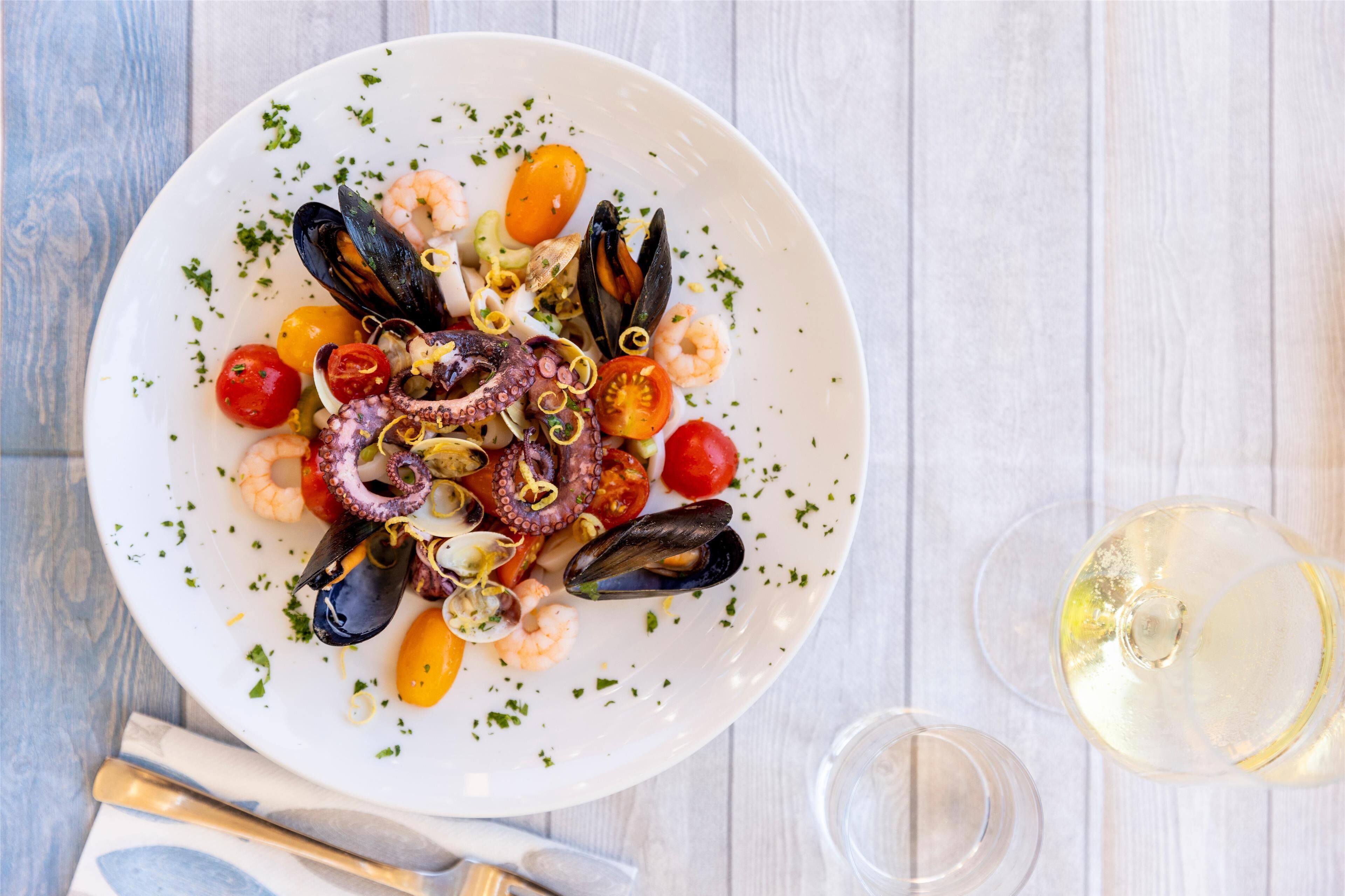 A seafood dish on a white plate with a fork and knife beside it.