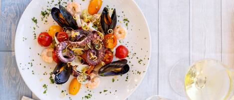 A seafood dish on a white plate with a fork and knife beside it.