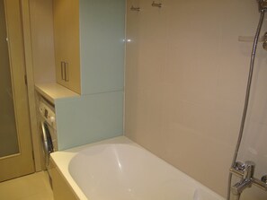 A bathroom with a bathtub, a shower, and a washing machine. - Luxurious Suite Athena Near To Beach (Malevizi)
