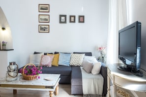 A living room with a sofa, a television, and framed pictures on the wall.