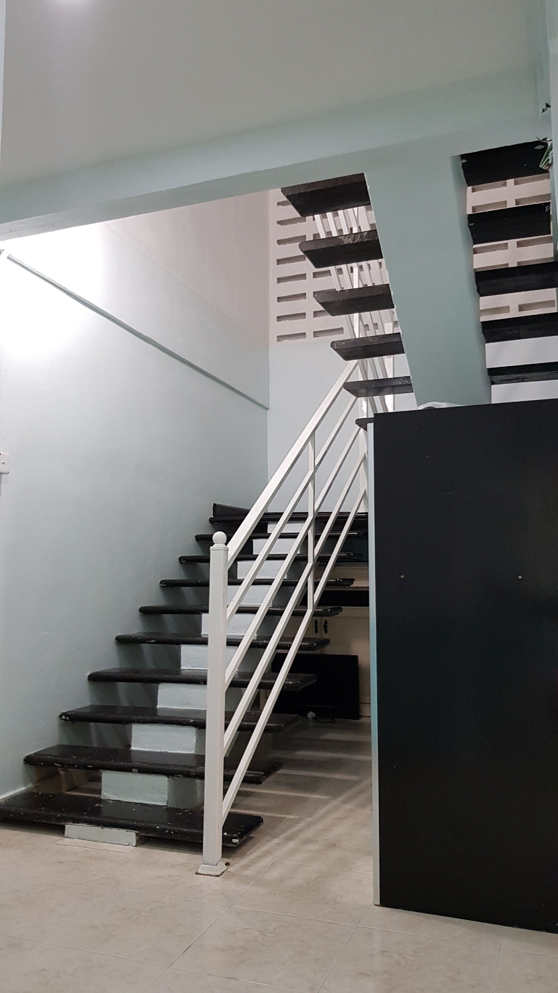 A staircase with white railings and dark steps, leading to an upper floor.