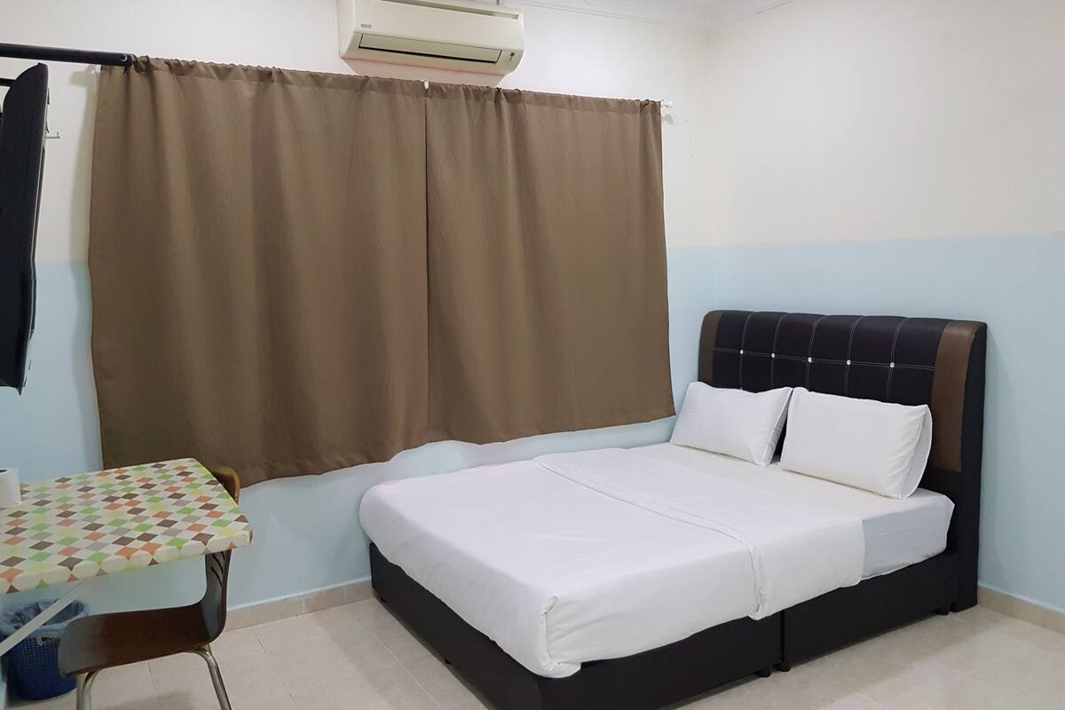 A bedroom with a bed, a table, and an air conditioning unit.