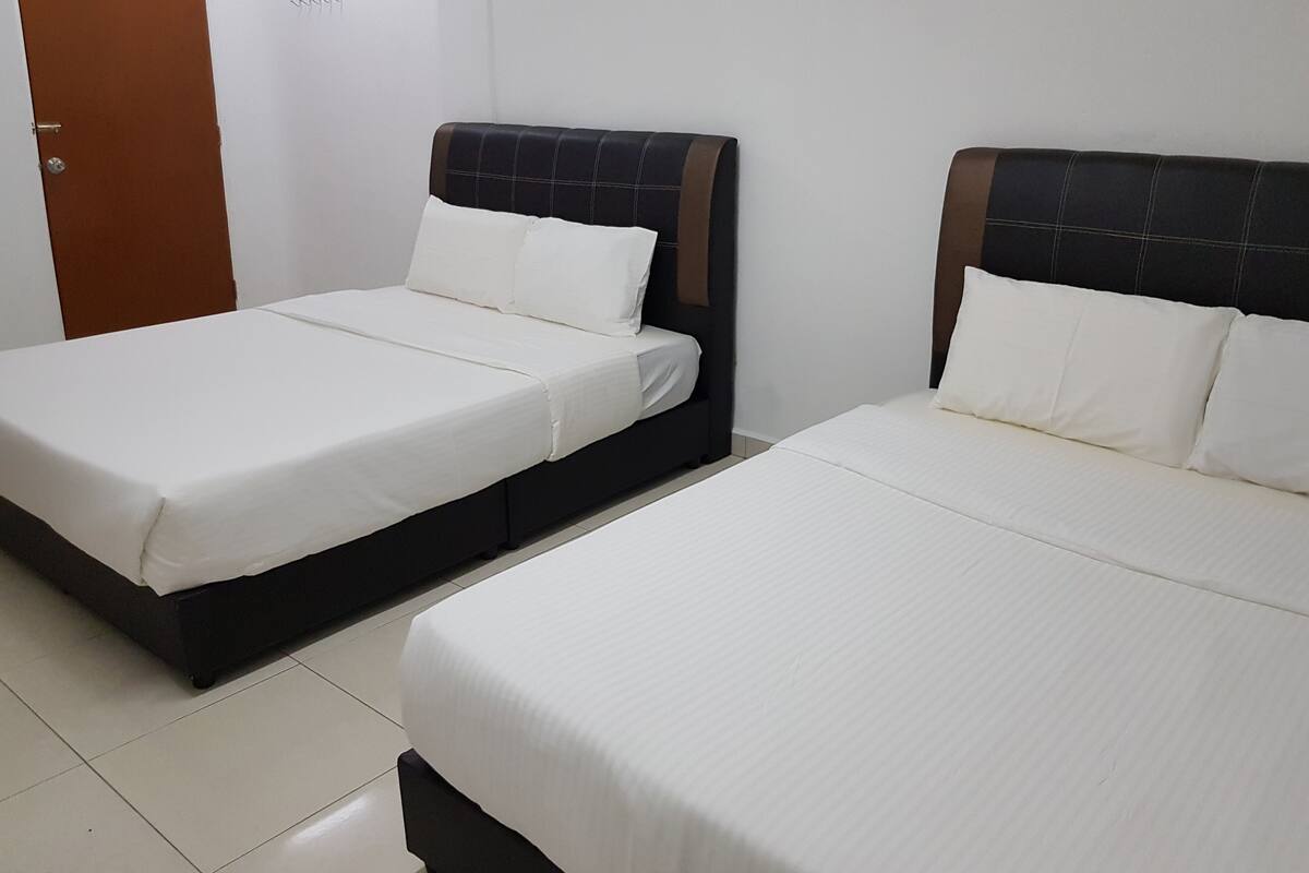 Two single beds with white linens and dark headboards in a room with white walls and a tiled floor.