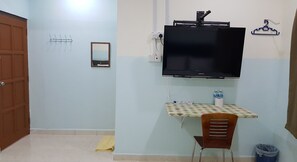 A room with a TV mounted on the wall, a small table with a chair, a mirror, and a clothes hanger. - OYO 89998 thank Q inn 2 (Kota Bharu)