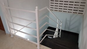 Eine weiße Metalltreppe mit einer schwarzen Fläche, die zu einem dunklen Boden führt.