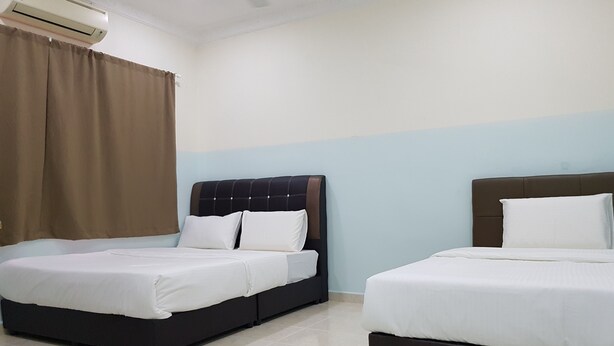 Ein Hotelzimmer mit zwei Betten, beigefarbenen Vorhängen und einer Klimaanlage.