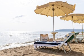 Une plage aménagée avec des chaises longues, des parasols et une table sur laquelle sont posés une serviette et un coussin.