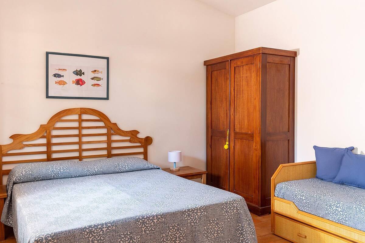 Ein Schlafzimmer mit zwei Betten, einem Holzschrank, einem gerahmten Bild von Fischen und einer Nachttischlampe.
