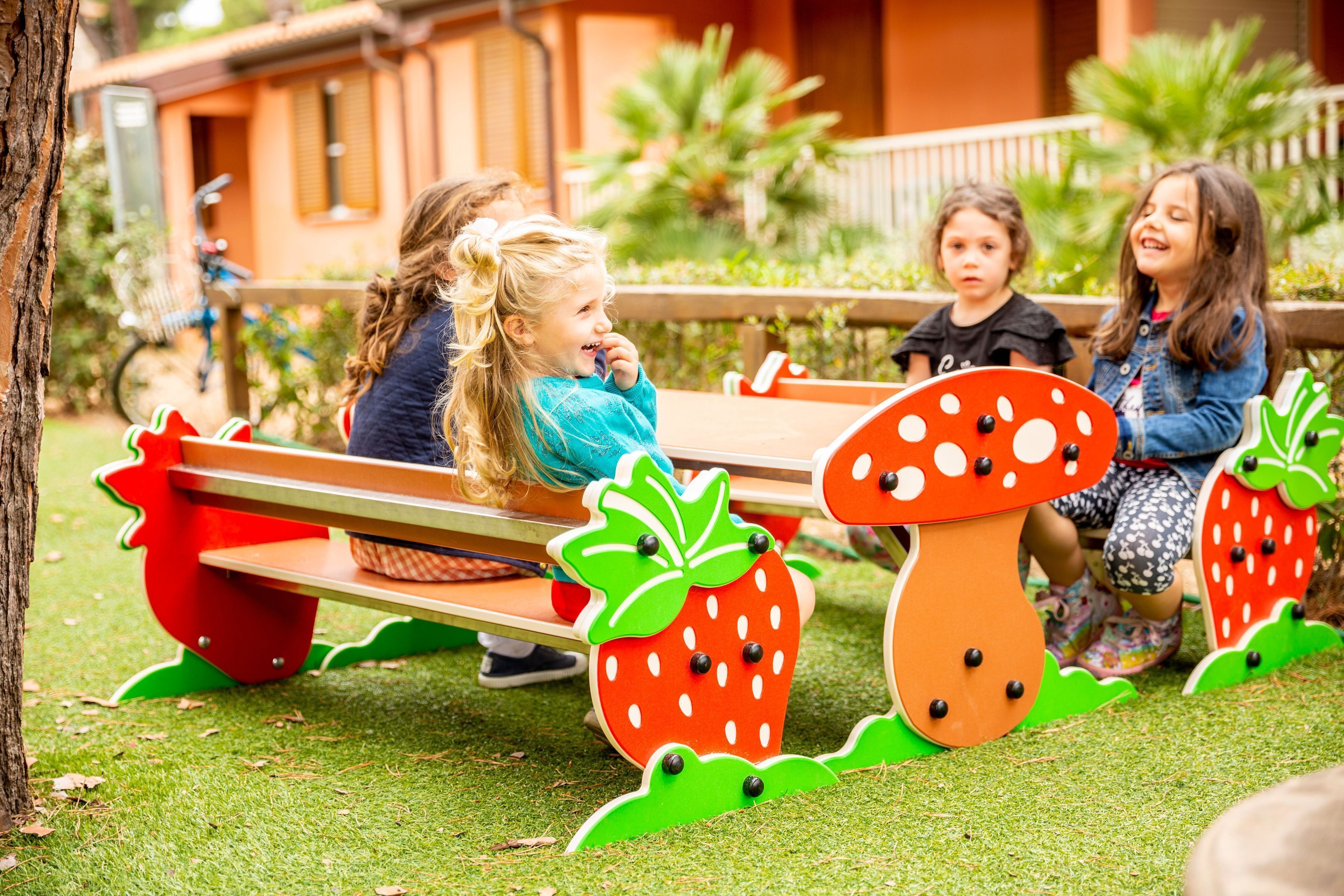 Des enfants jouent sur un banc en bois orné d’un motif représentant des fraises.