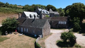 A stone building with a gravel driveway and a small lawn area. - old farmhouse of the manor (siouville hague)
