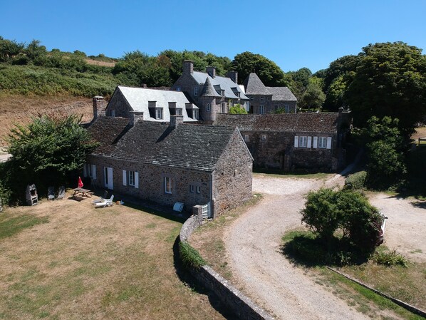 A stone building with a gravel driveway and a small lawn area.