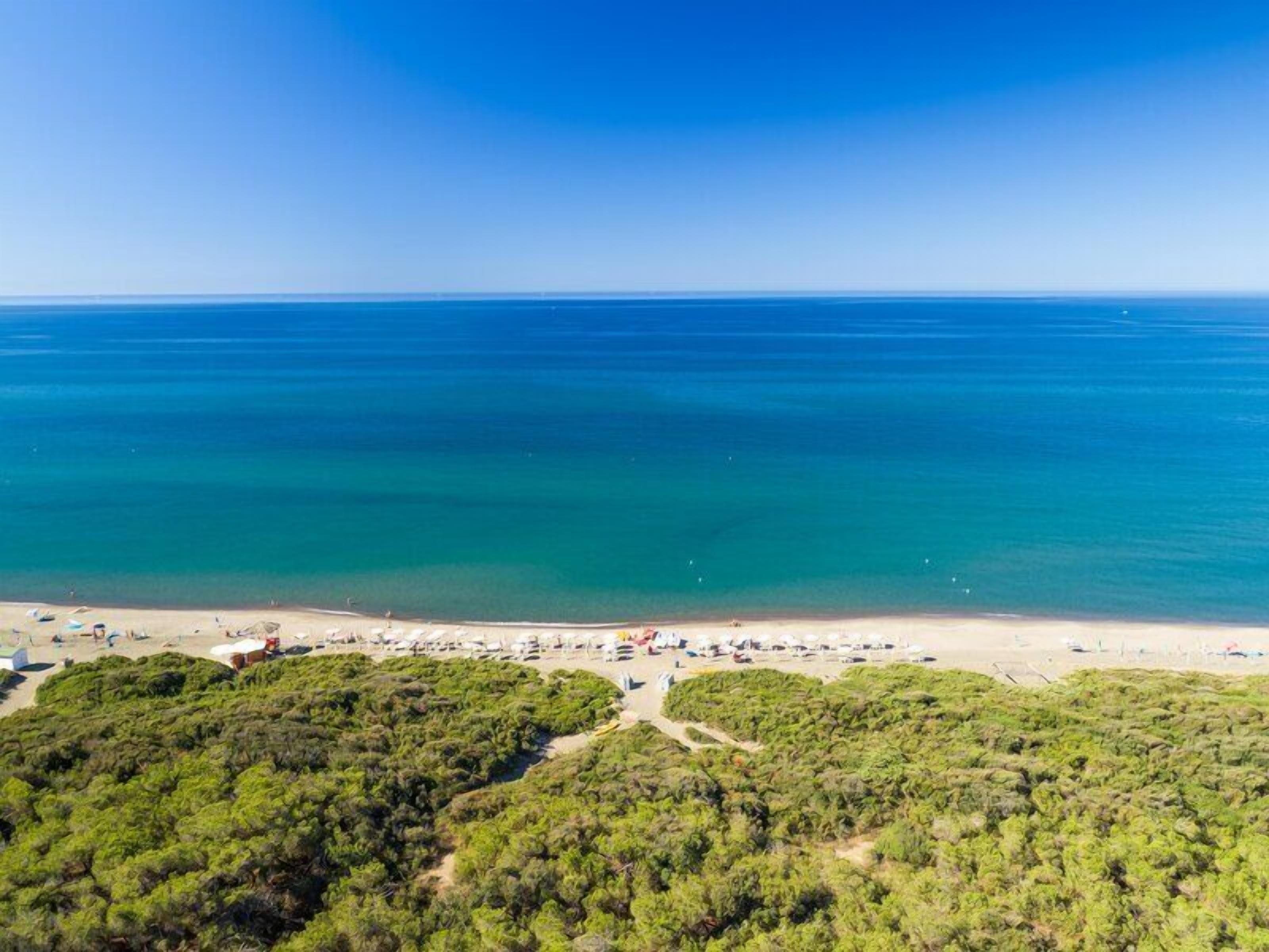 Privat strand, svart sandstrand, solstolar och parasoller