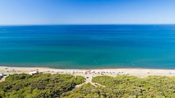 Privat strand, svart sandstrand, solstolar och parasoller