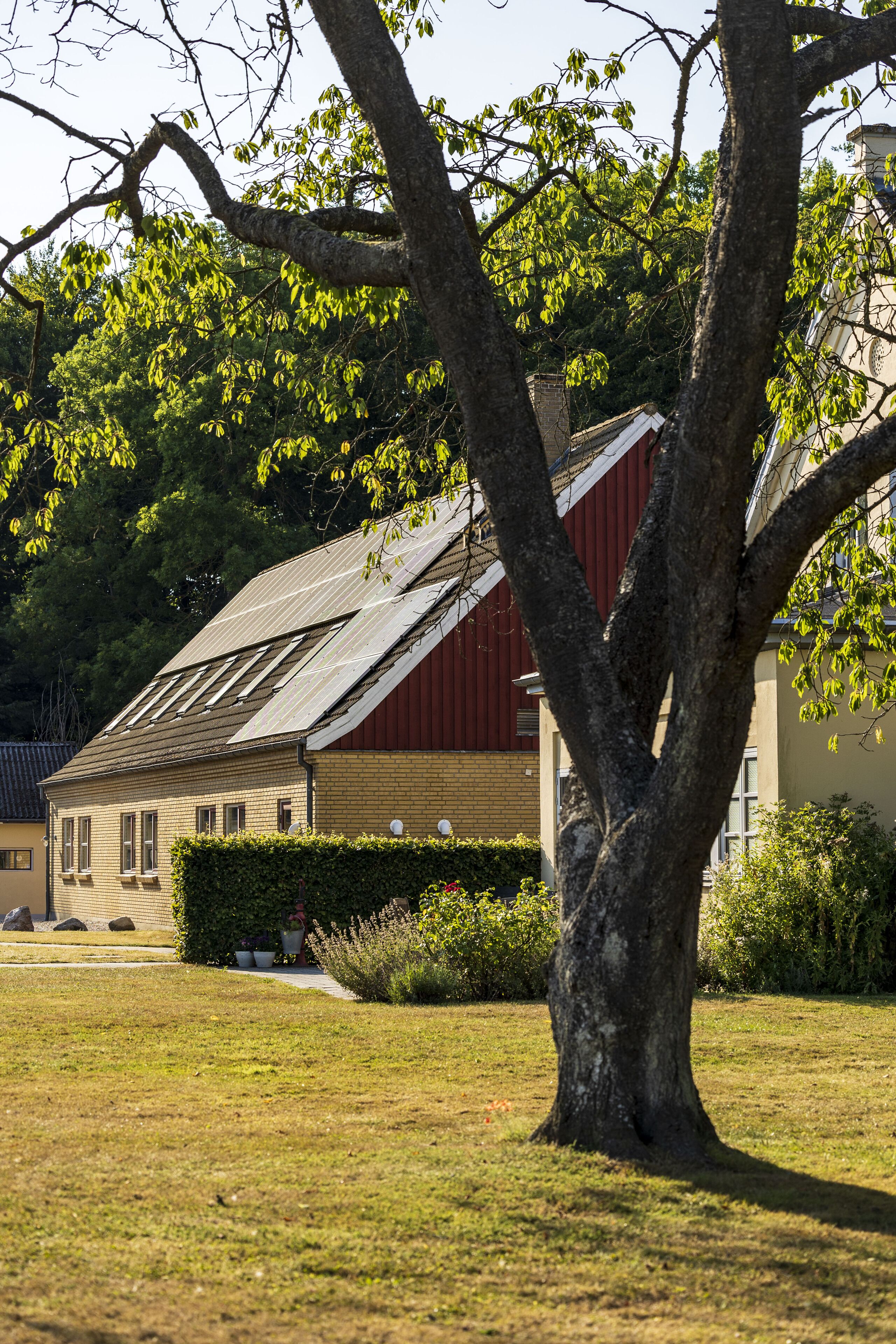 A building with a red roof, surrounded by a grassy area and trees.