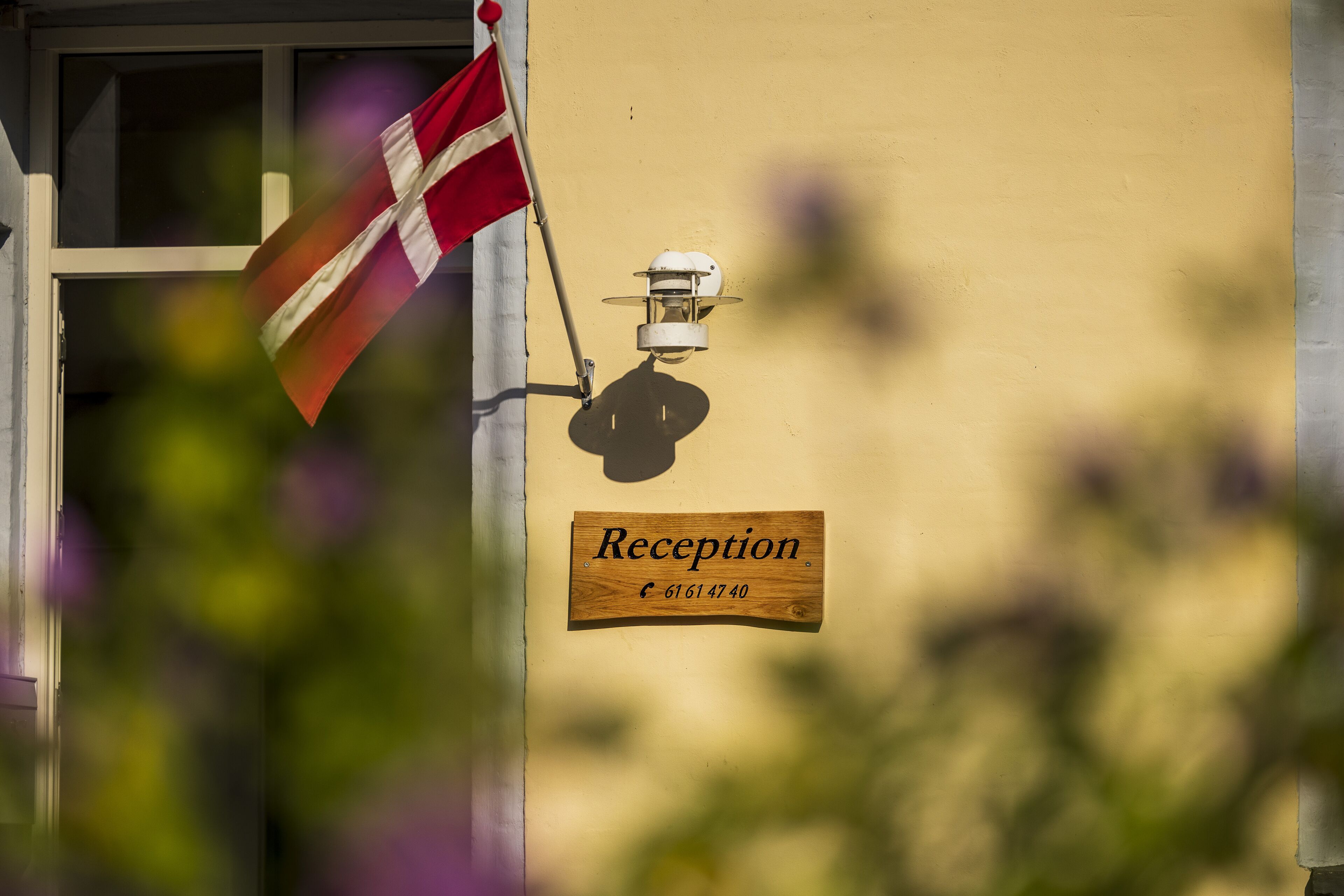 A reception sign with a flag and a light fixture on a building wall.