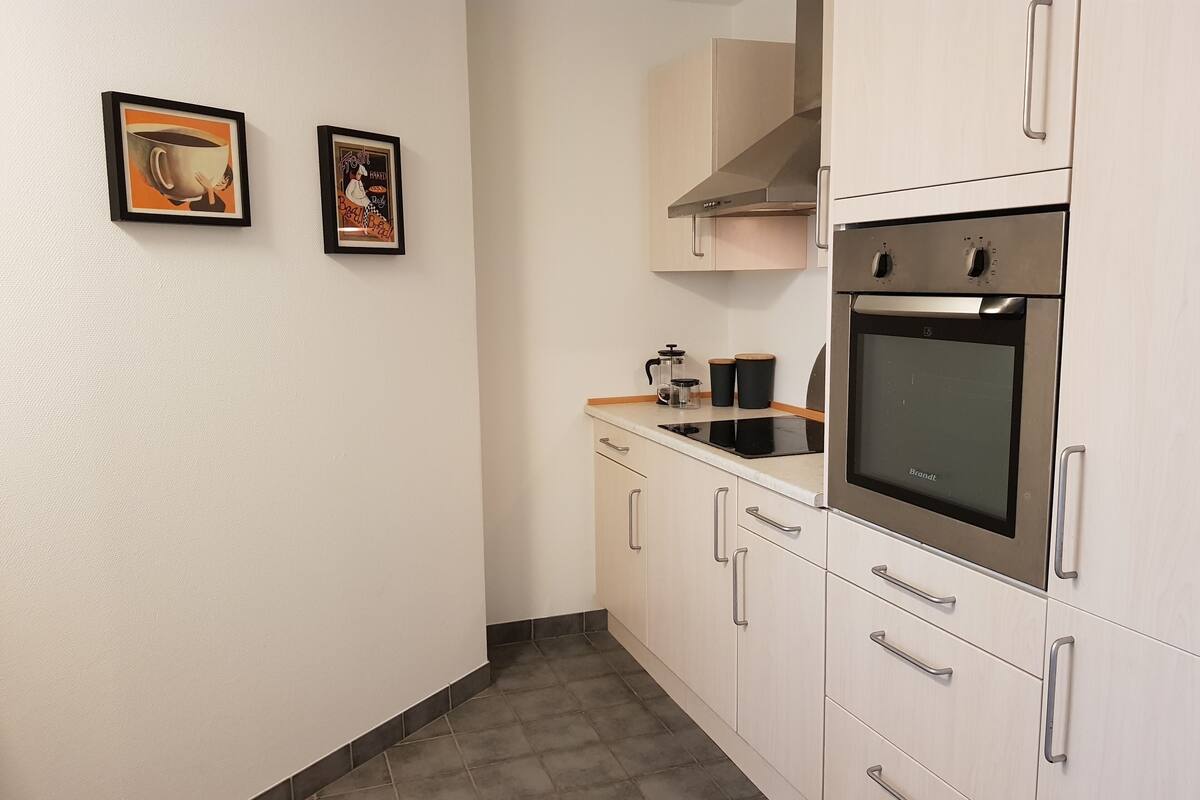 A modern kitchen with stainless steel appliances, white cabinetry, and a tiled floor.