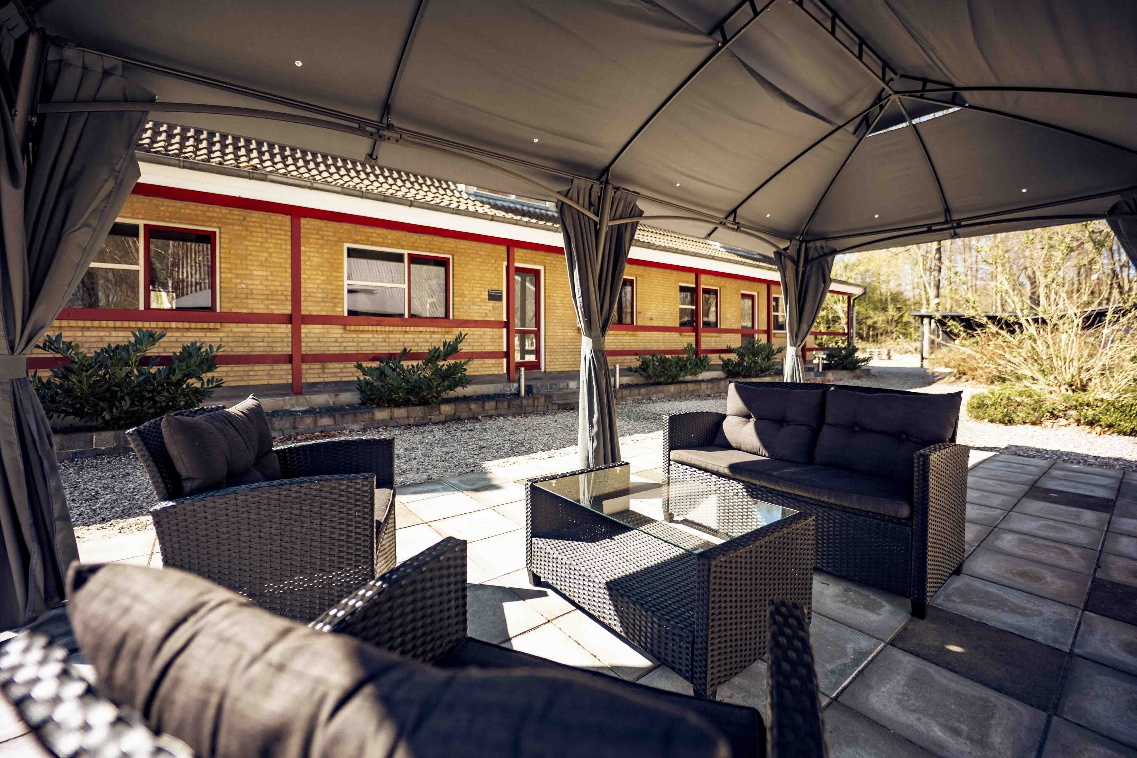 Un espace extérieur aménagé en terrasse, avec des meubles en osier et une partie couverte.