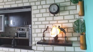A kitchen with a brick wall, a clock, and a decorative shelf with a lit candle.