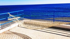 A hammock on a balcony overlooking the sea.