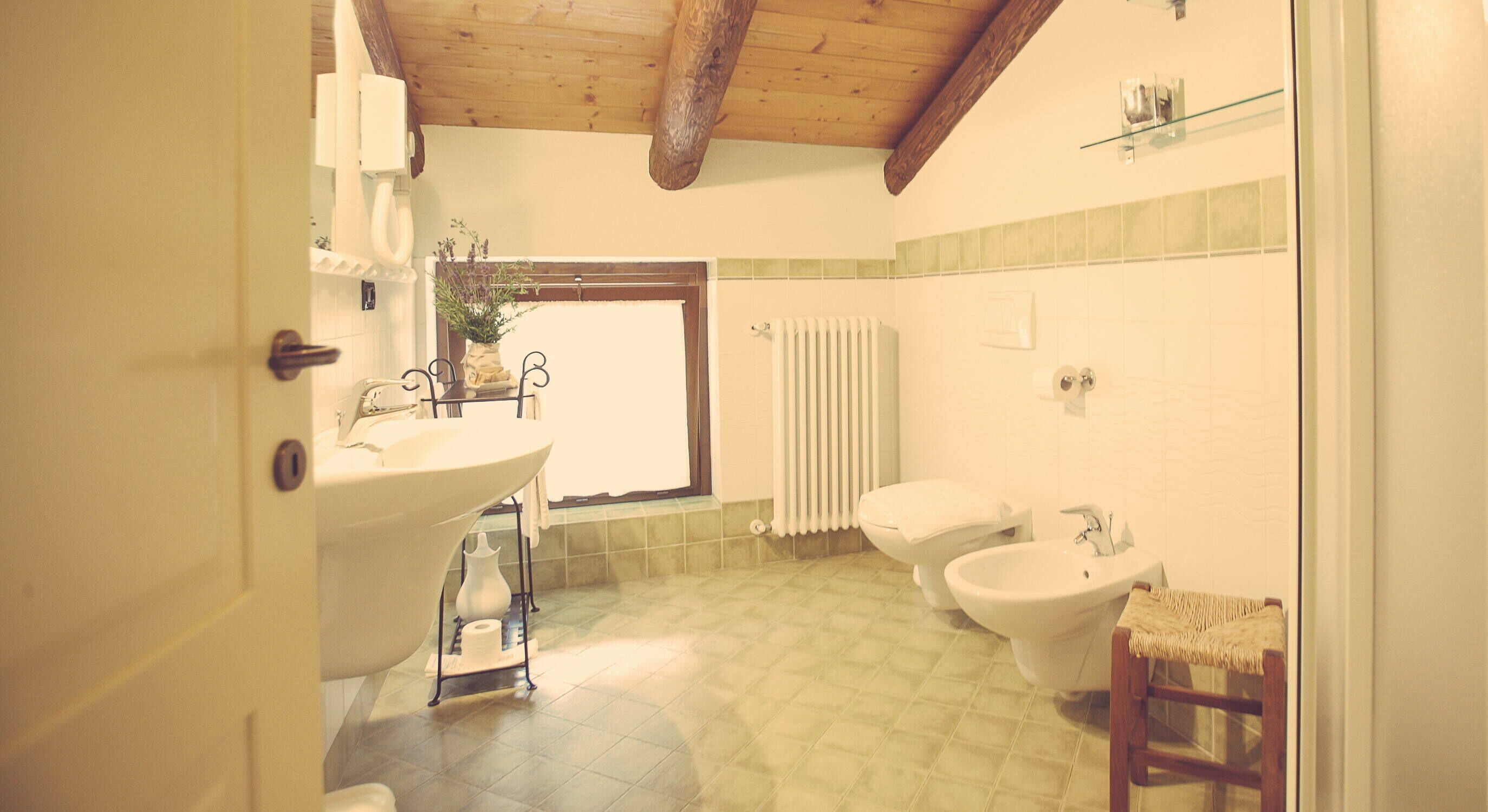 A bathroom with a large sink, toilet, bidet, and a window.