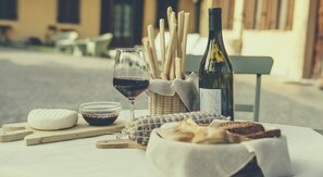 A table with a bottle of wine, a glass of red wine, breadsticks, a bowl of olives, and a piece of cheese. - Casa Ressia (Alba)