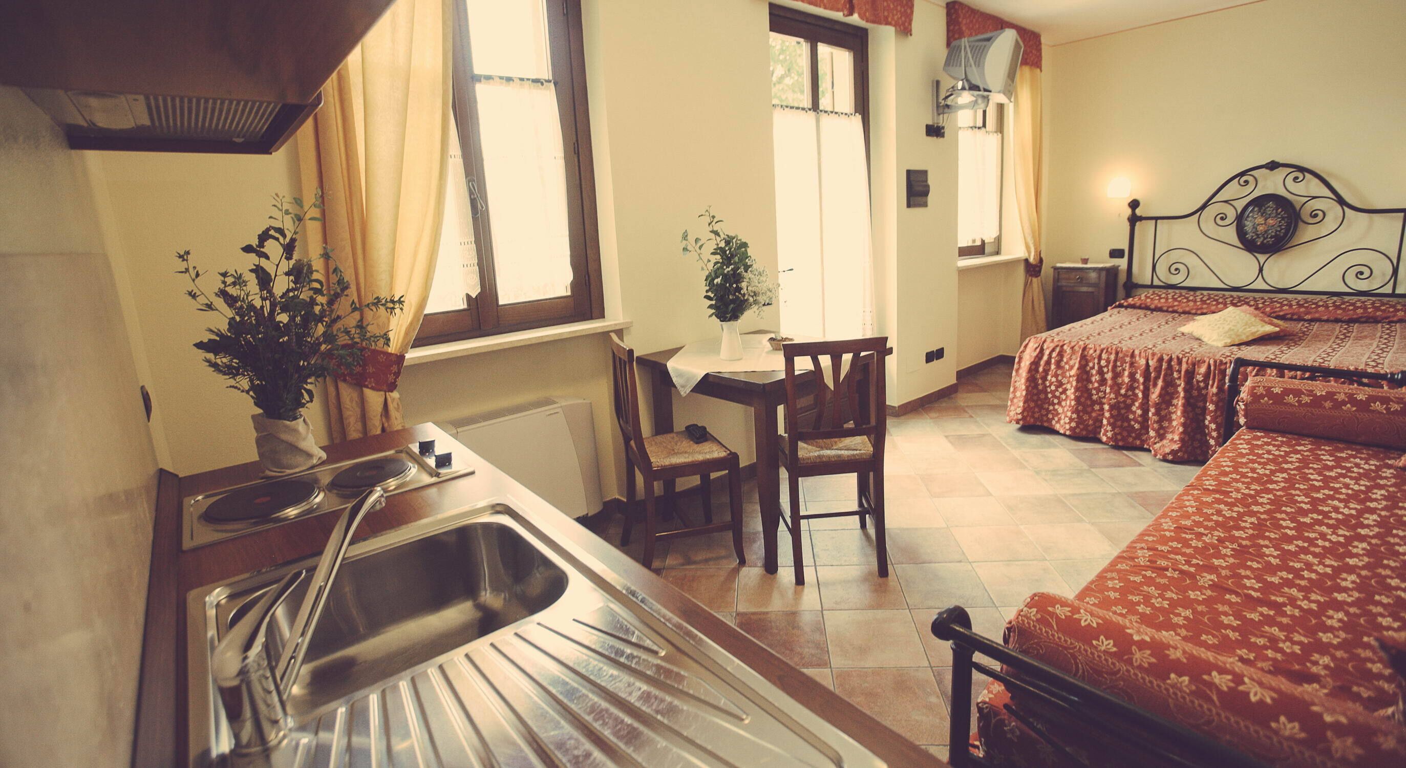 A small, cozy room with a bed, a desk, and a sink.