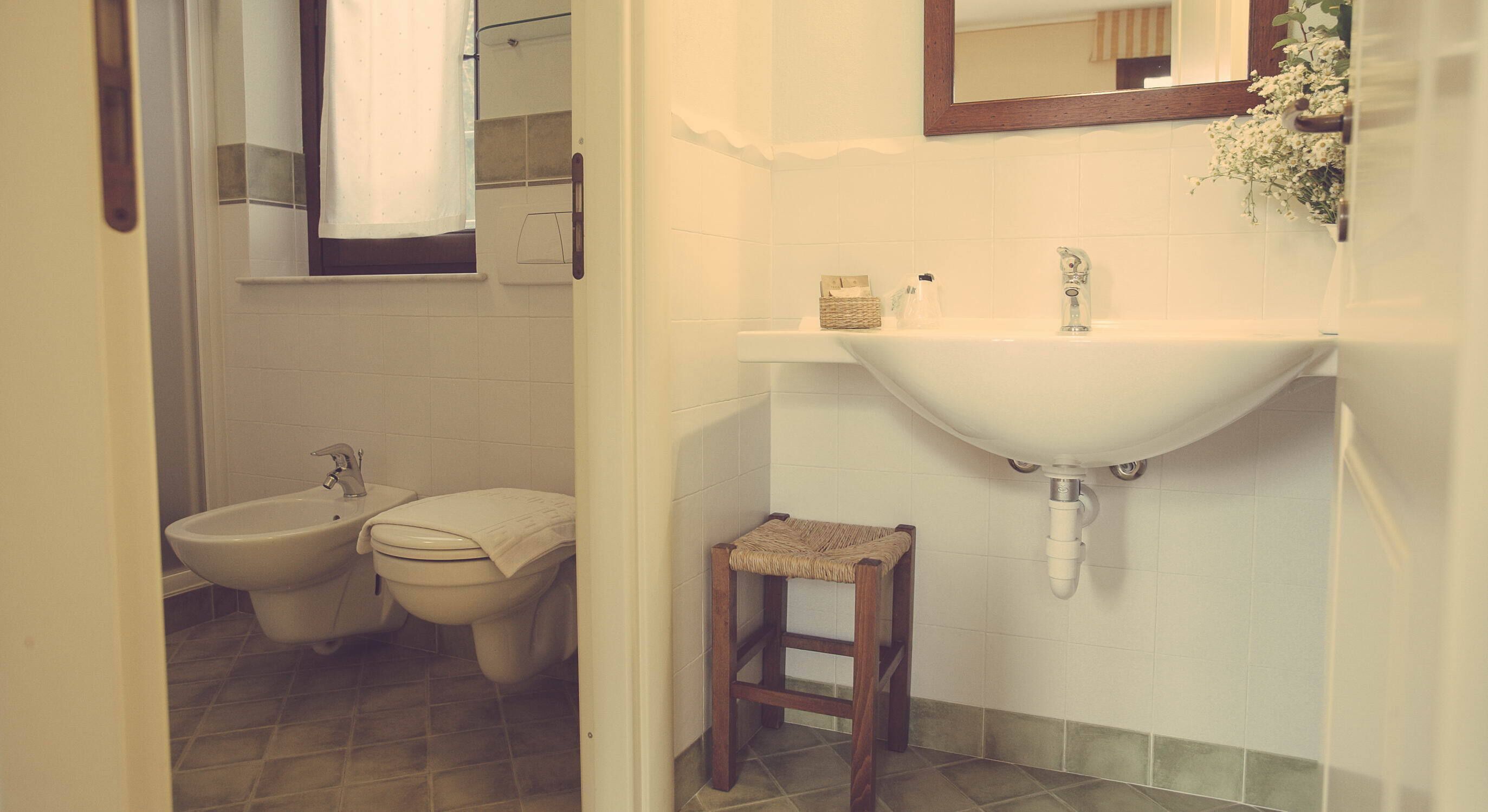 A bathroom with a bidet, a sink, and a small stool.