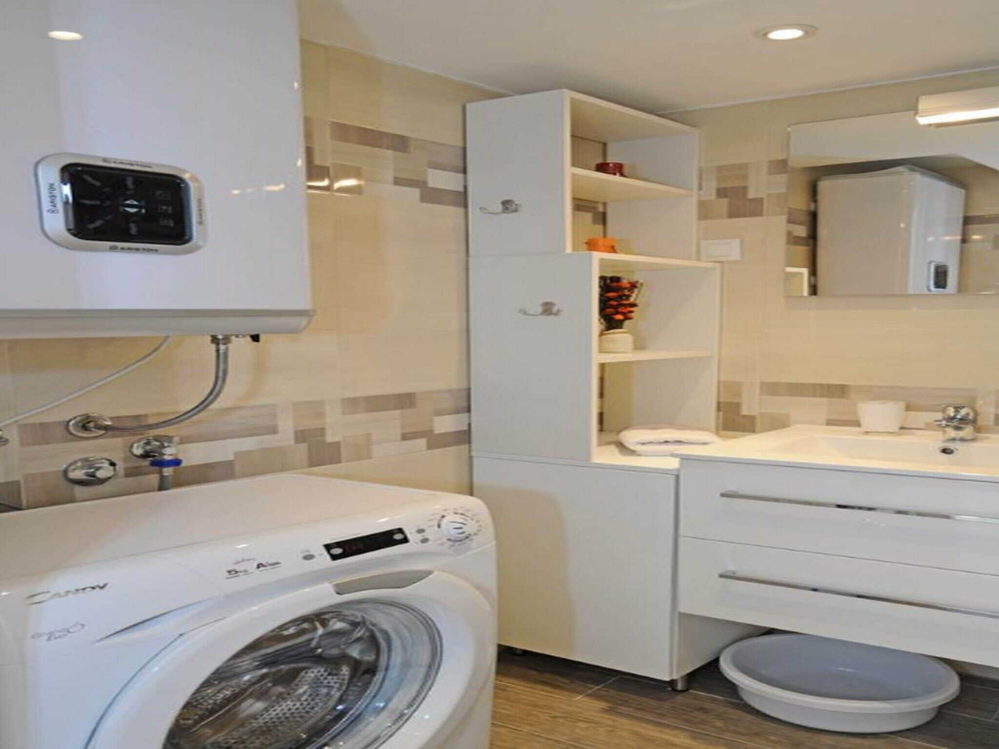 A compact bathroom with a washing machine, a toilet, and a sink.