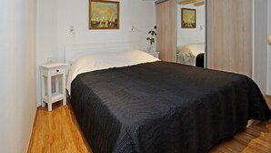 Quarto com cama grande, mesa de cabeceira, penteadeira e guarda-roupa de portas deslizantes.