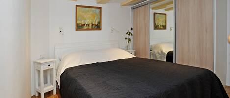 Une chambre à coucher avec un grand lit, une table de chevet, une commode et un placard à portes coulissantes.