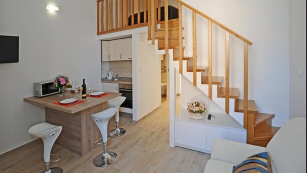 Um apartamento moderno com cozinha, sala de jantar e escada de madeira.
