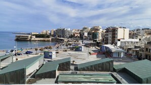 A coastal cityscape with a mix of residential and commercial buildings, a prominent fort structure, and a clear view of the sea. - Andreas Cozy Lovely House (Heraklion)